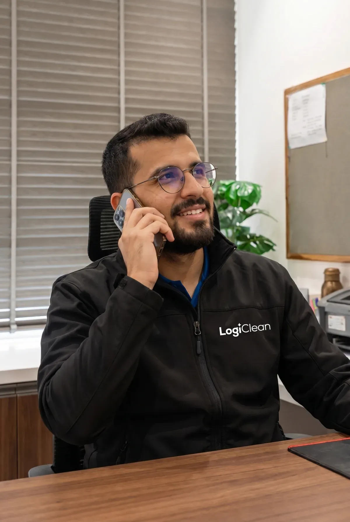 A Logiclean team member in a branded jacket taking a quote enquiry over the phone at the office.